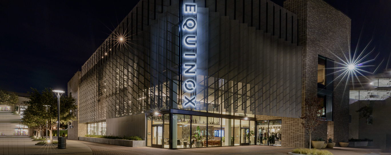 The equinox building is lit up at night.