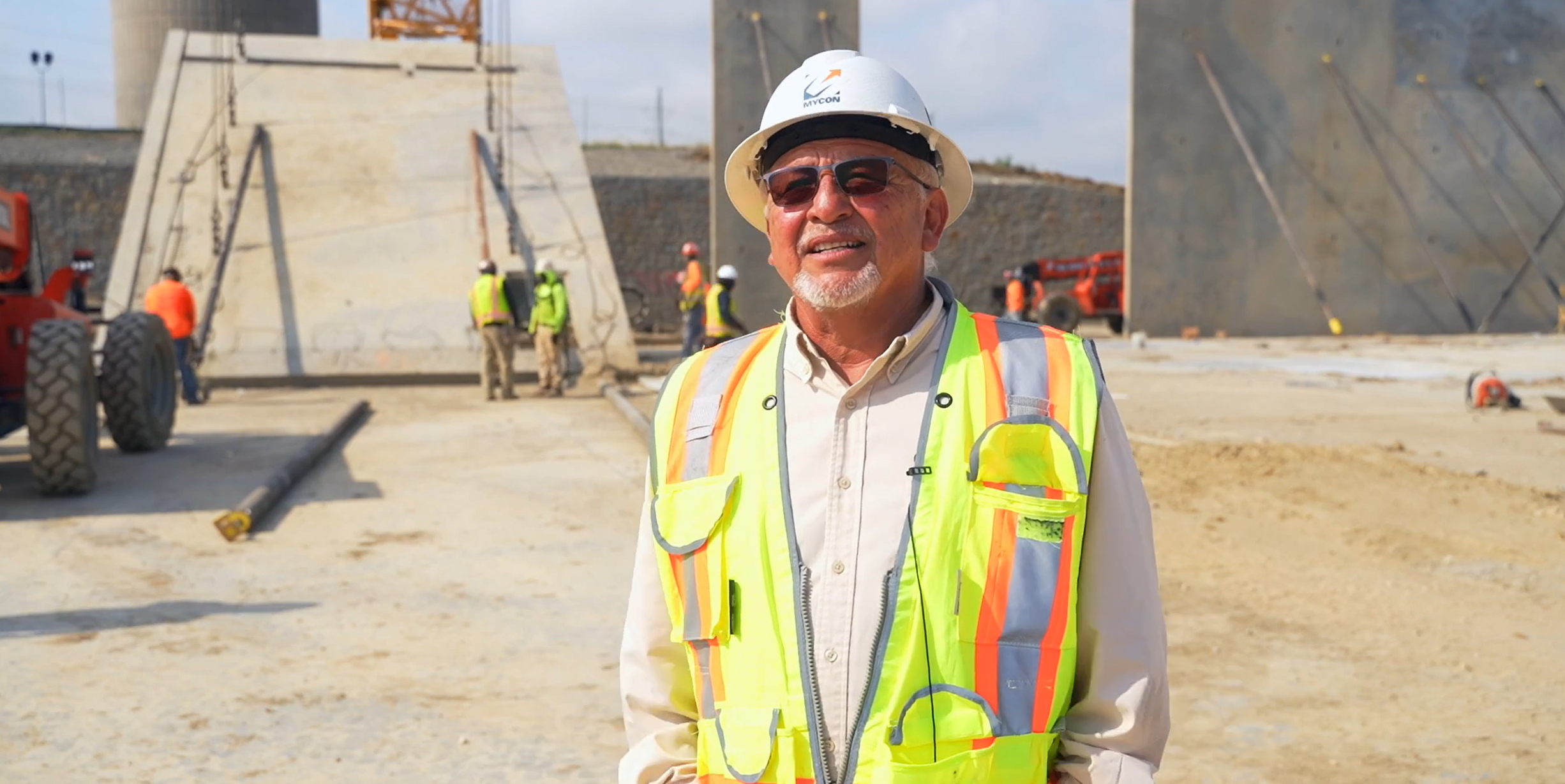 A man in a hard hat standing in front of a construction site.
