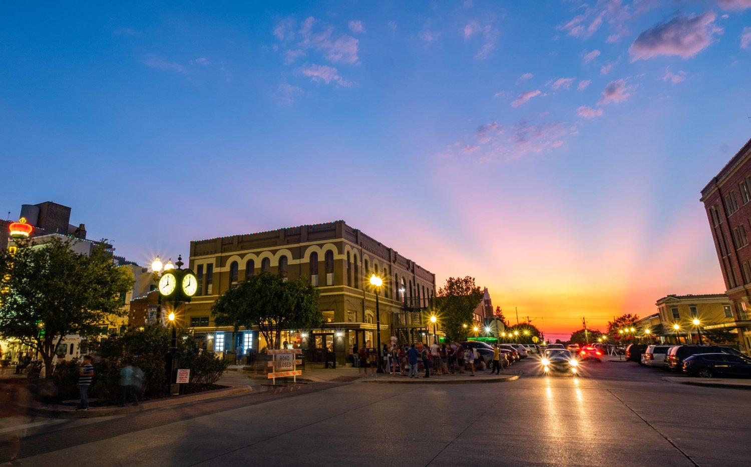 A city street at dusk in a small town.