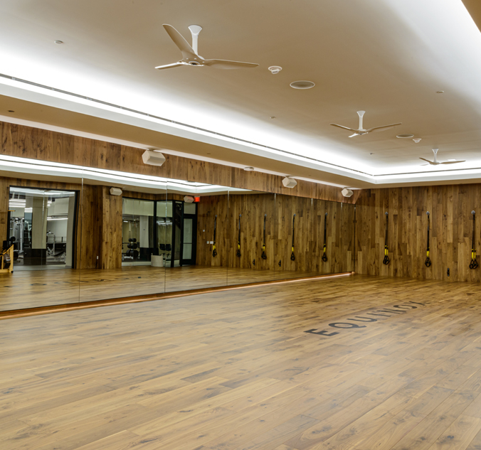 An empty dance studio with wood floors and mirrors.