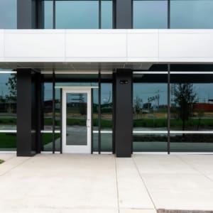 An office building with glass doors and a grassy area.