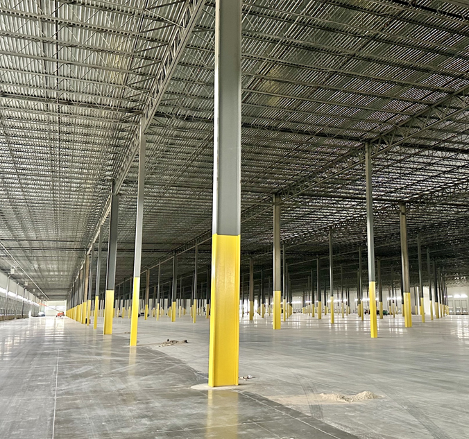 The inside of a large warehouse with yellow poles.