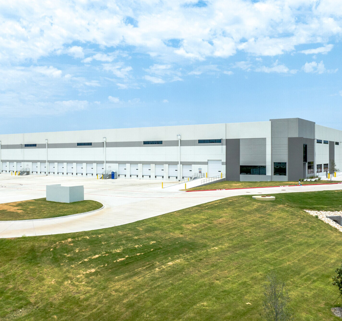 A large warehouse with a grassy field in the background.