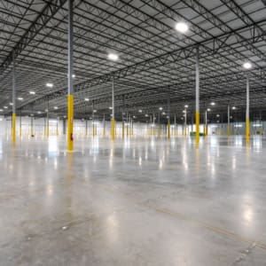 A large warehouse with concrete floors and yellow poles.