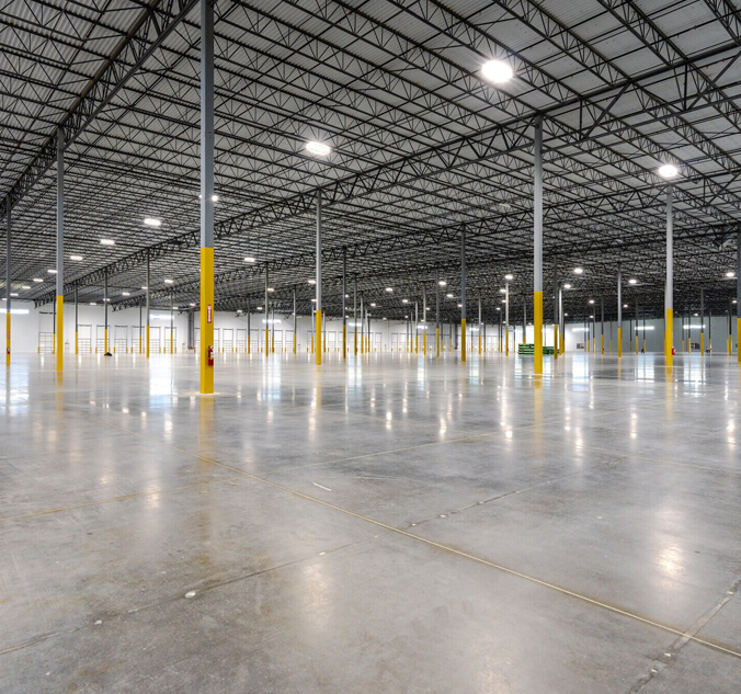 A large warehouse with concrete floors and yellow poles.