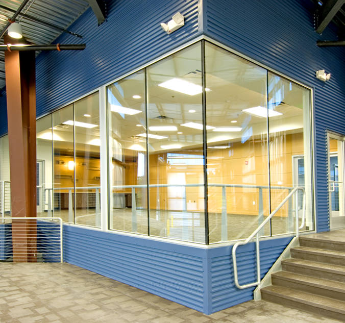 A blue building with glass walls and stairs.