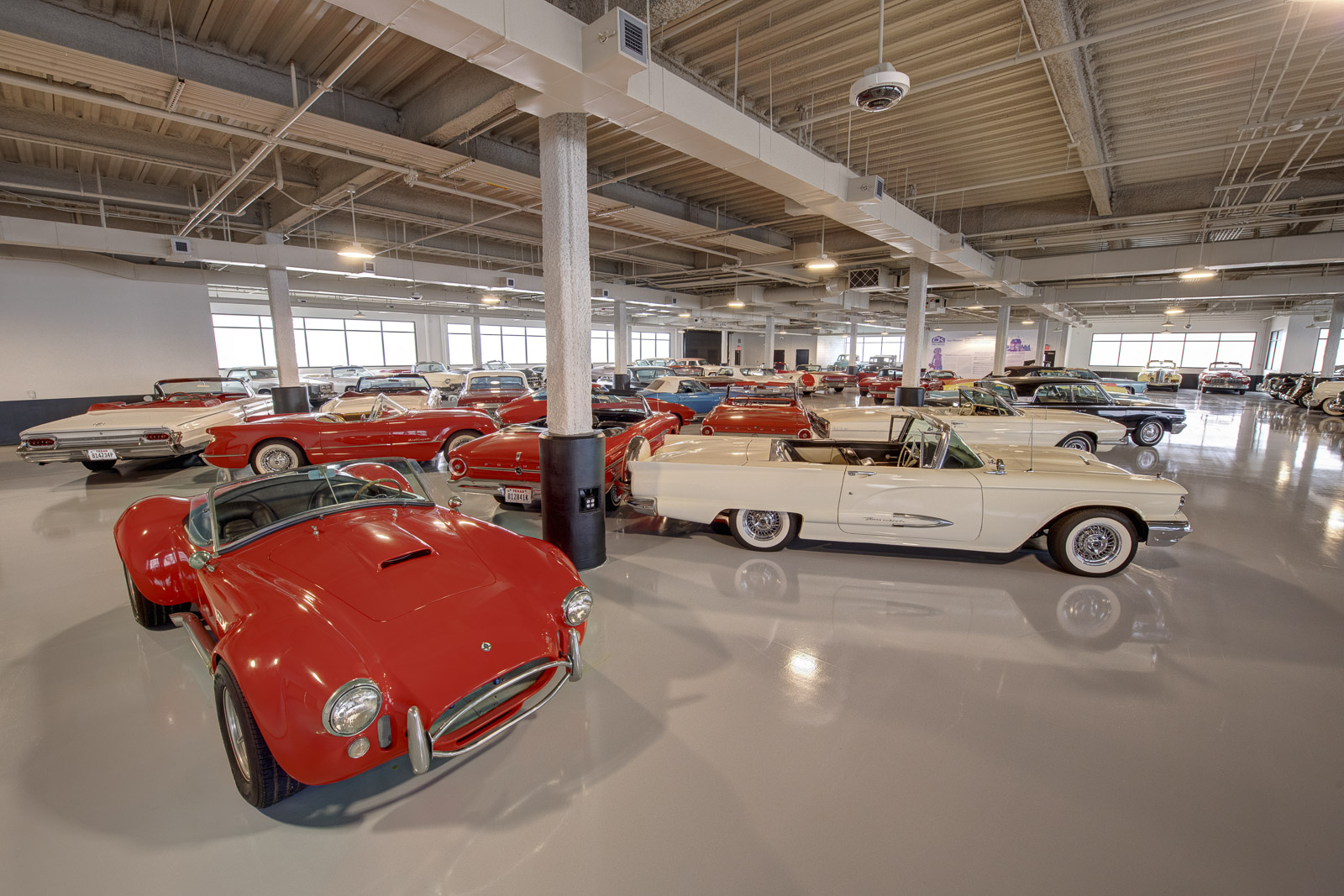 Many classic cars are parked in a large building.