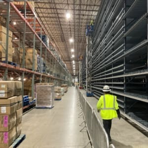 A worker walks through a warehouse full of boxes and pallets.