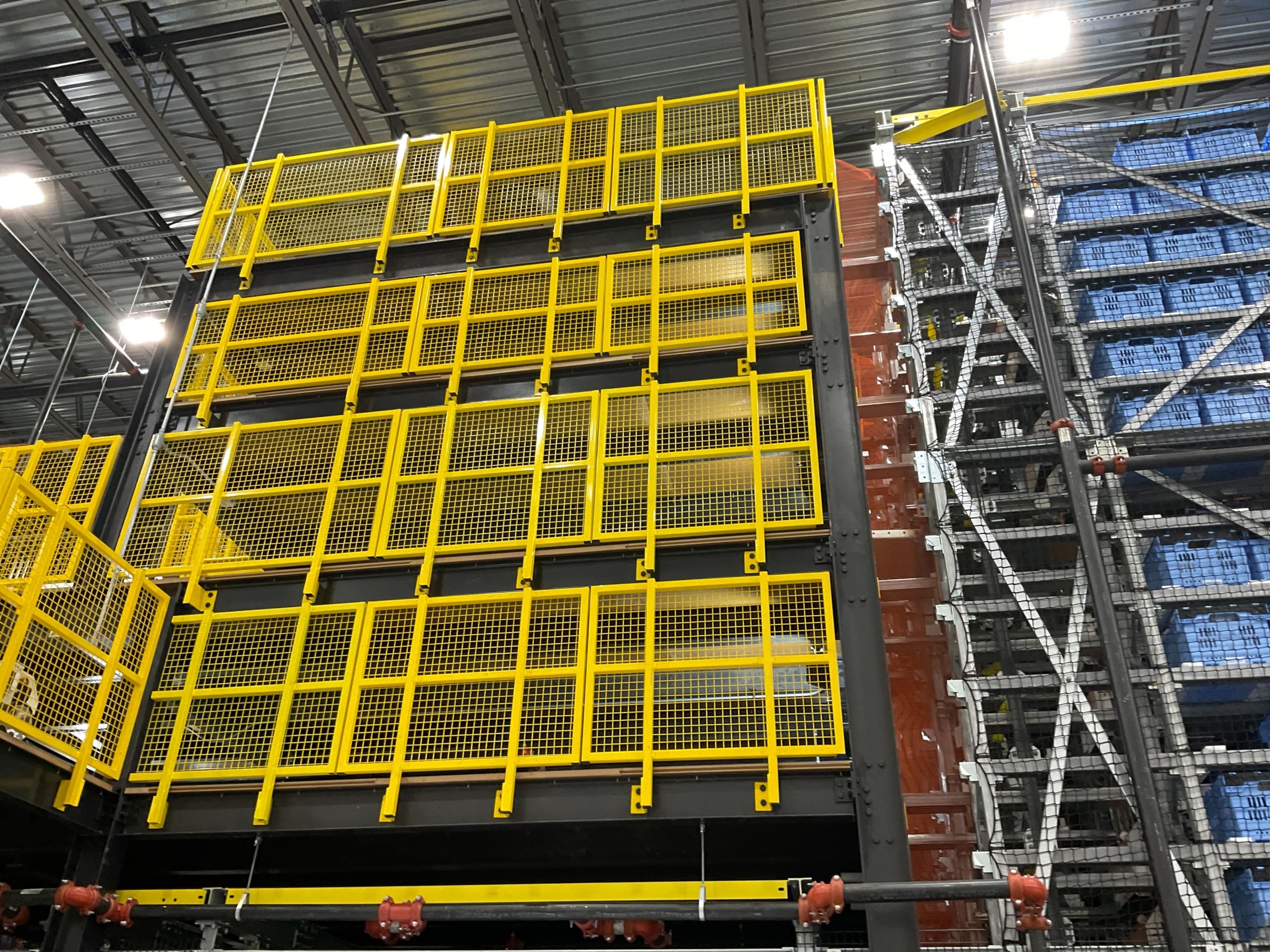 A large warehouse with yellow crates and shelves.