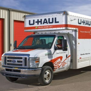 A white moving truck parked in front of a garage.