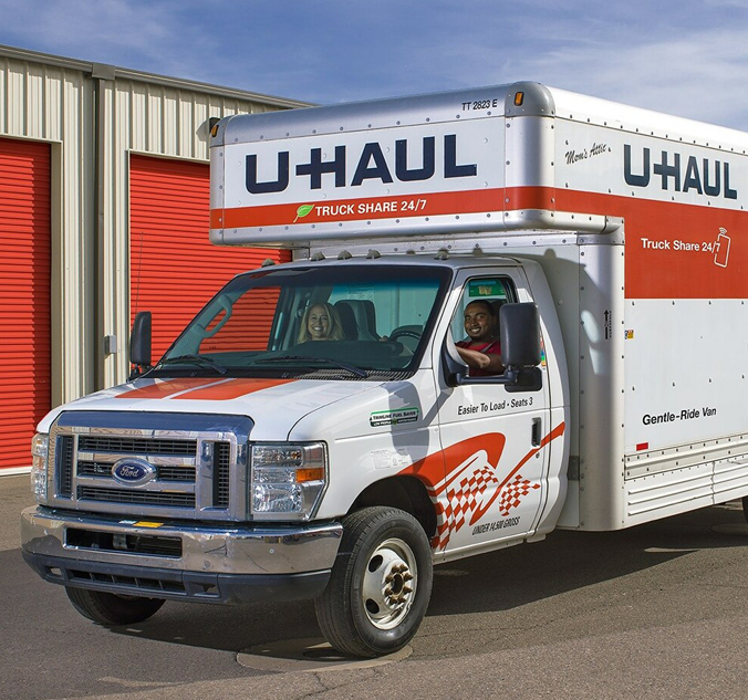 A white moving truck parked in front of a garage.