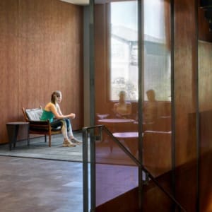 A woman sitting on a bench in a lobby.