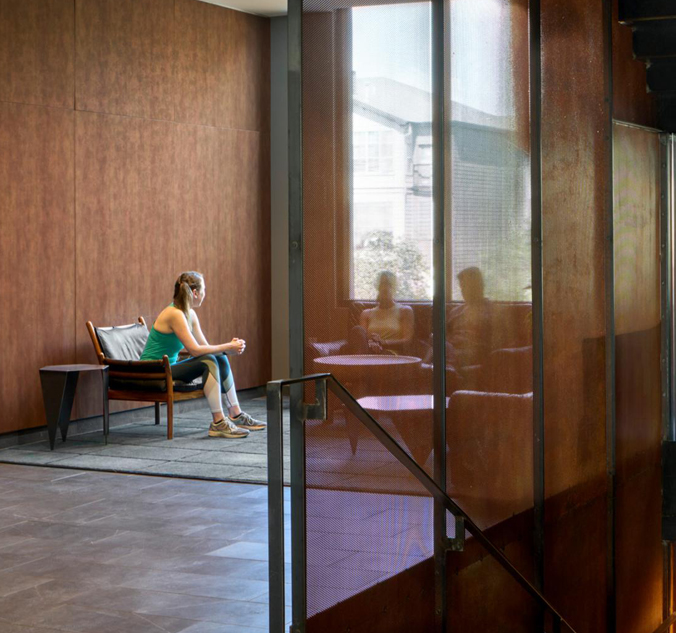 A woman sitting on a bench in a lobby.