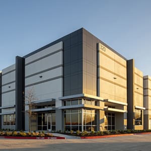 A large warehouse building in the middle of a parking lot.