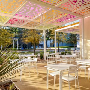 A patio with tables and chairs under a colorful canopy.