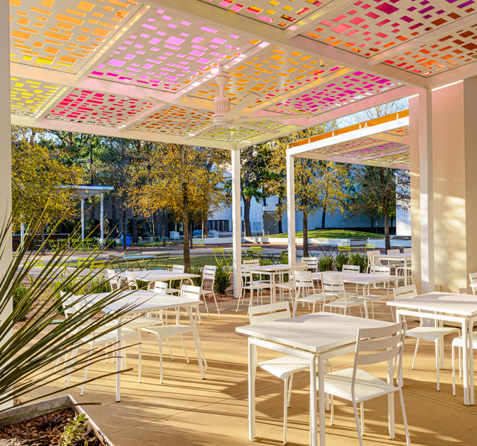 A patio with tables and chairs under a colorful canopy.