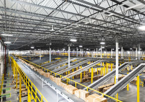 The inside of an amazon warehouse with yellow conveyor belts.