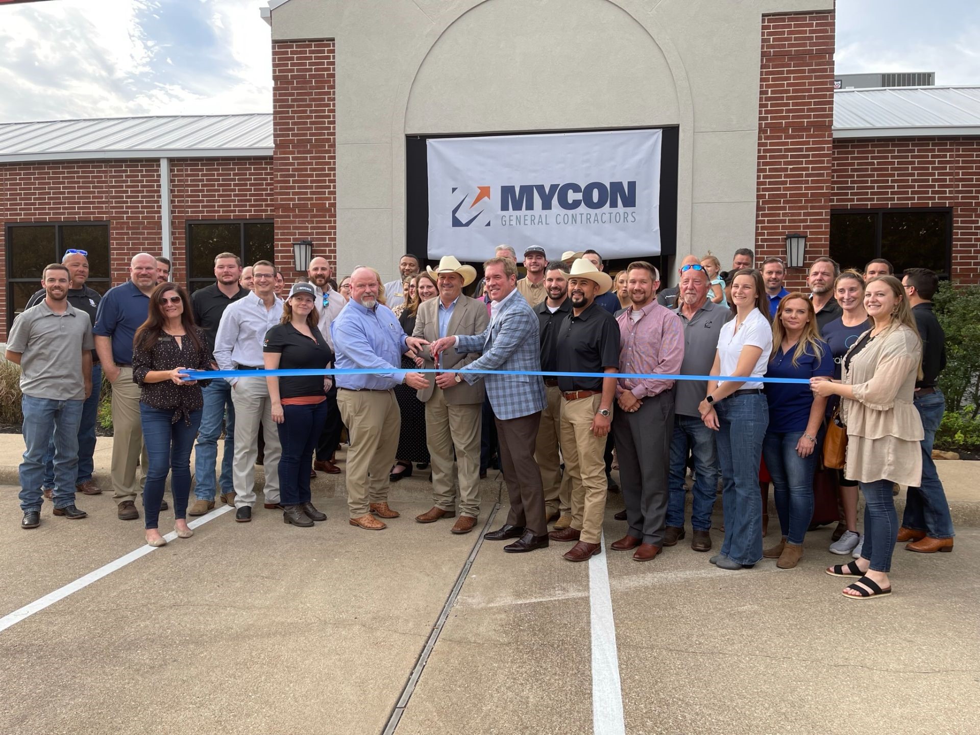 A group of people cutting a ribbon in front of a building.