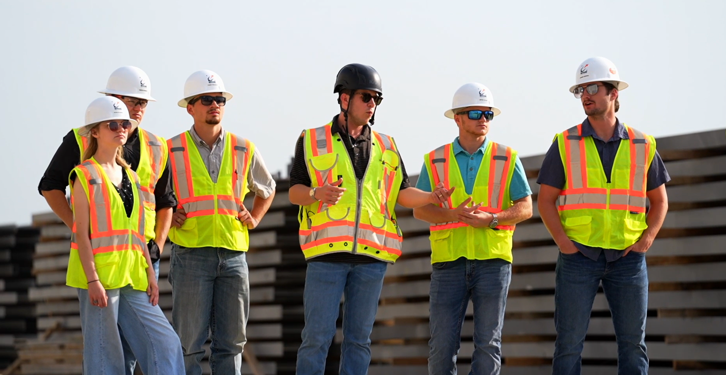 Group of construction workers in hard hats and high-visibility vests at a construction site.