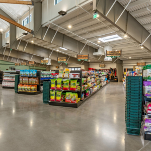Interior view of a spacious, well-lit store with organized aisles displaying various gardening supplies and pet food, indicating clearly labeled sections like "Plant Food," "Garden Solutions," and "Wild Bird.