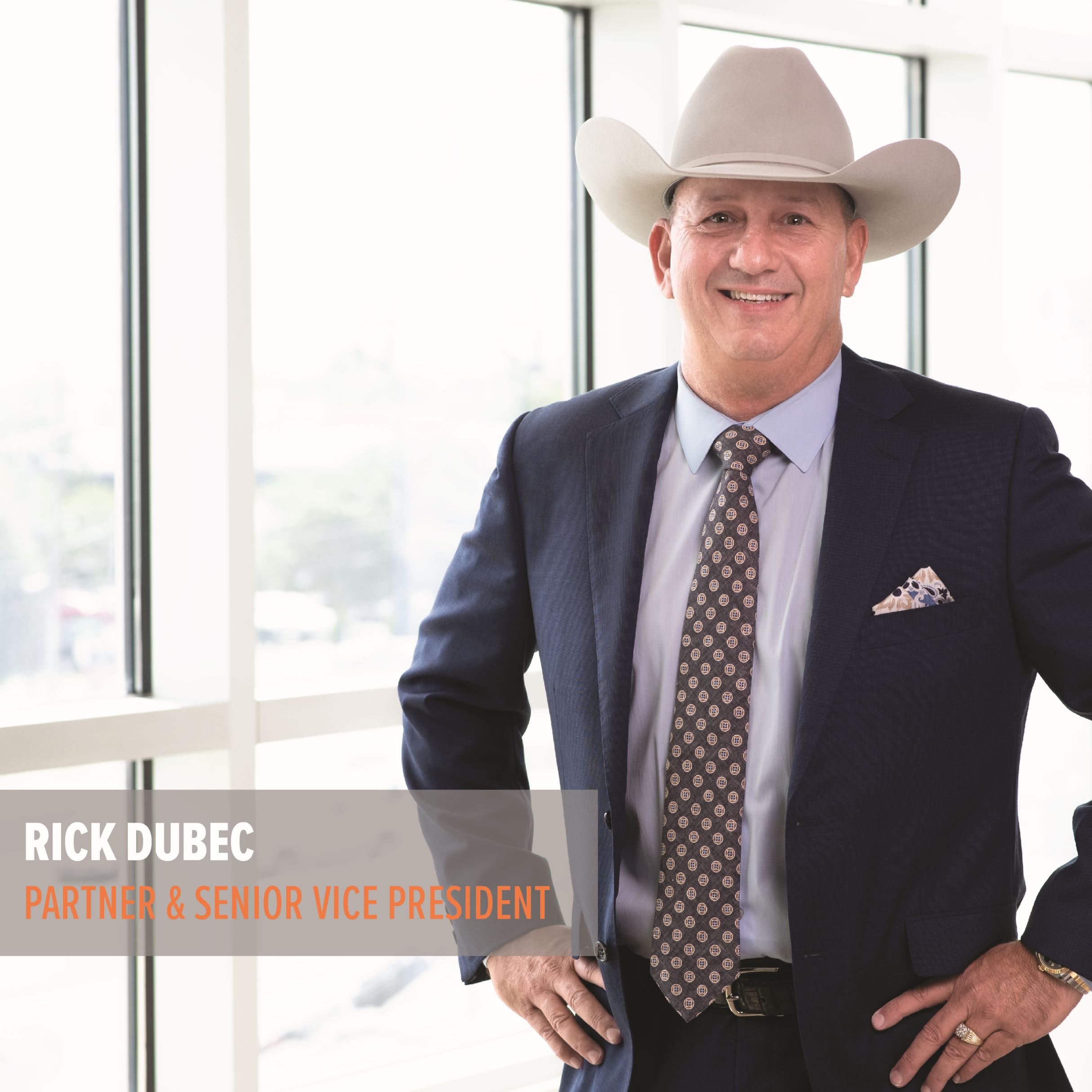 A man in a suit and cowboy hat with a name and title caption.