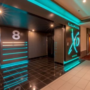 A modern cinema entrance with neon lights displaying "CineMark XD Auditorium" and a large number 8 on the wall, indicating the theater hall number.