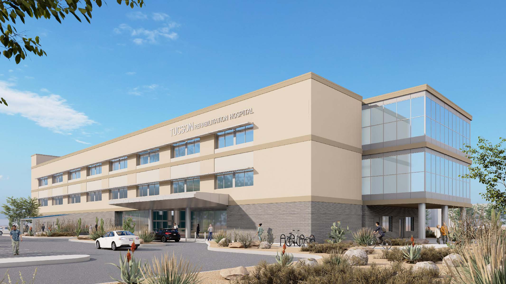 A multi-story hospital building with large windows, a main entrance with a canopy, and a few parked vehicles in front. Desert landscaping surrounds the facility.