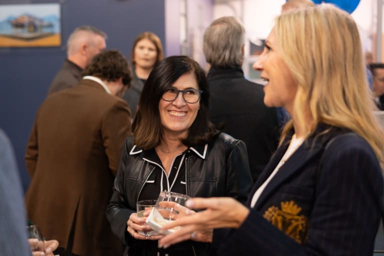 People engaging in conversation at an event, holding drinks in their hands.