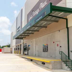 A commercial building with a covered loading dock, multiple bay doors, safety rails, and red storage containers in the background, ideal for U-Haul of East Denton Construction operations.