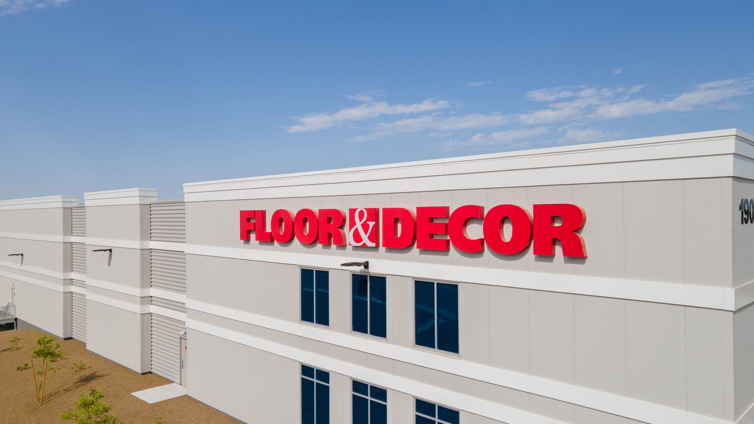 The exterior of a white building with large red “FLOOR & DECOR”