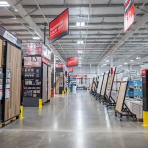 A wide aisle in Home Depot San Antonio West displays various flooring samples and materials, with shelves and signage visible under bright lighting.