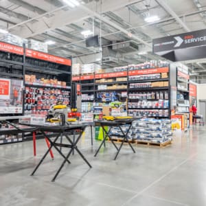 A hardware store interior with tools, building materials, and supplies organized on shelves; saws and equipment displayed on tables in the foreground, perfect for any construction project.