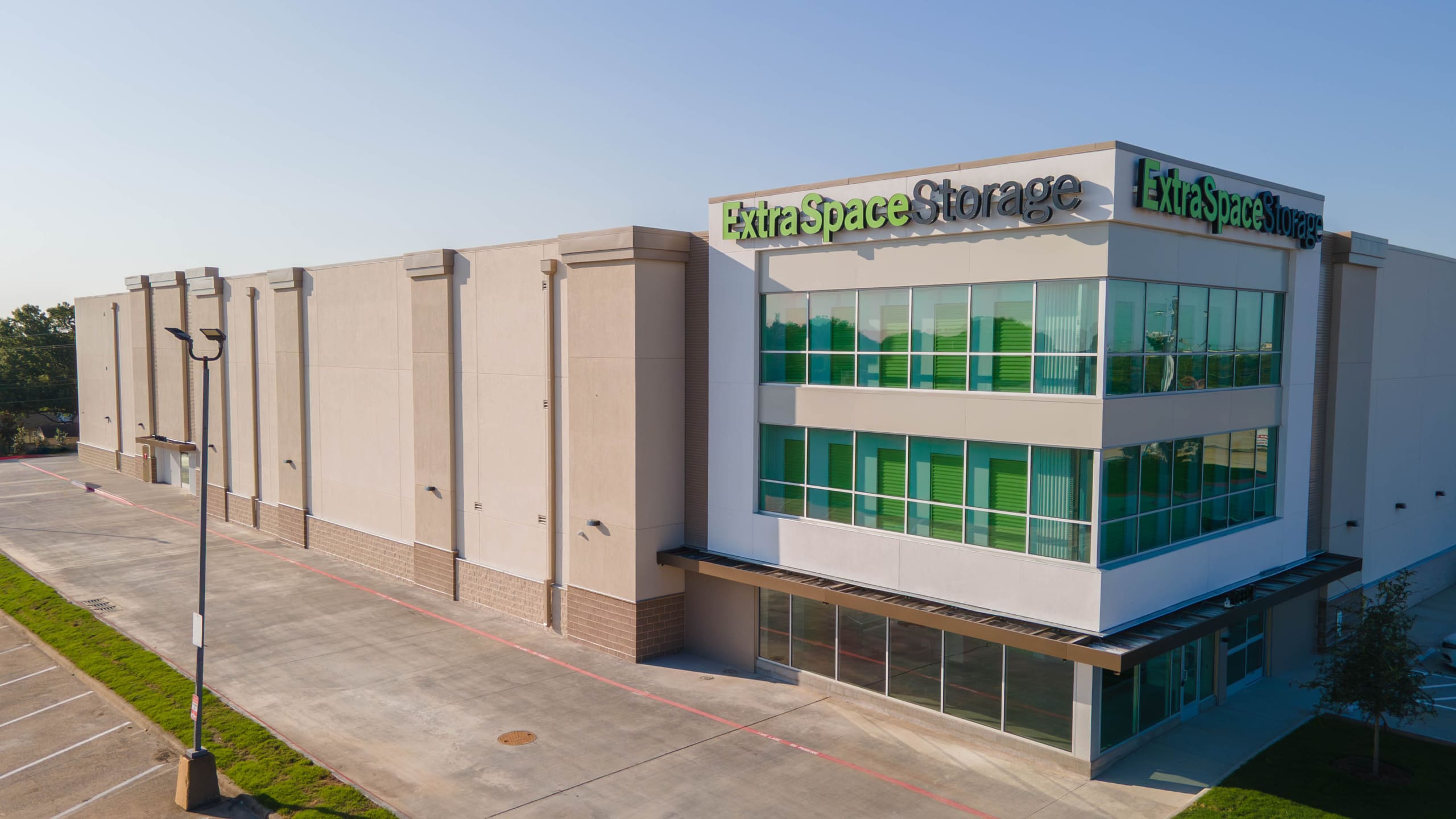 A modern Extra Space Storage facility with multiple floors and green window accents, all under a clear sky.