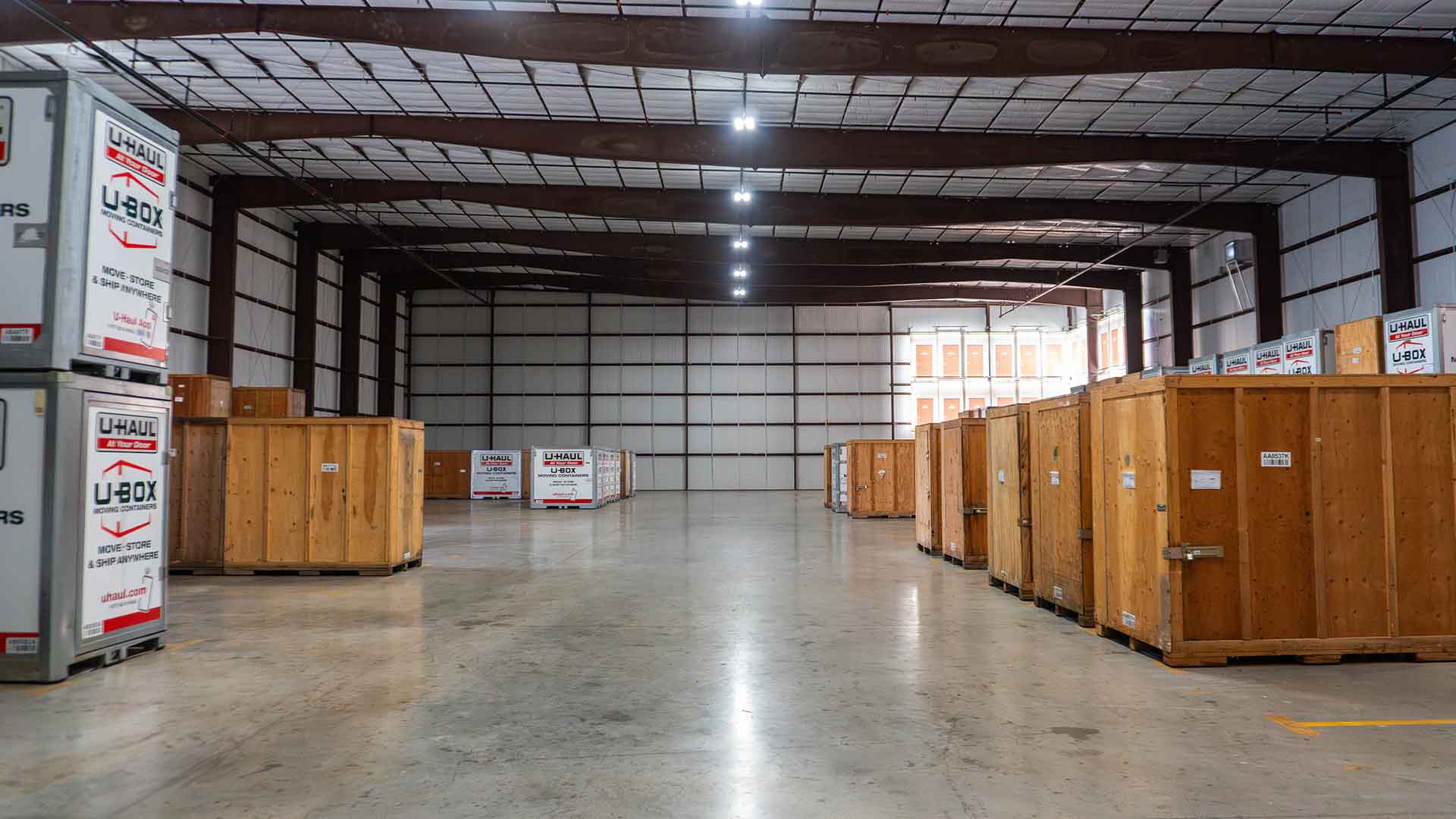 Large indoor storage facility at U-Haul of McKinney with wooden crates and U-Haul U-Box containers arranged along the walls on a polished concrete floor. U-Haul, Self Storage, Warehouse, Storage Building